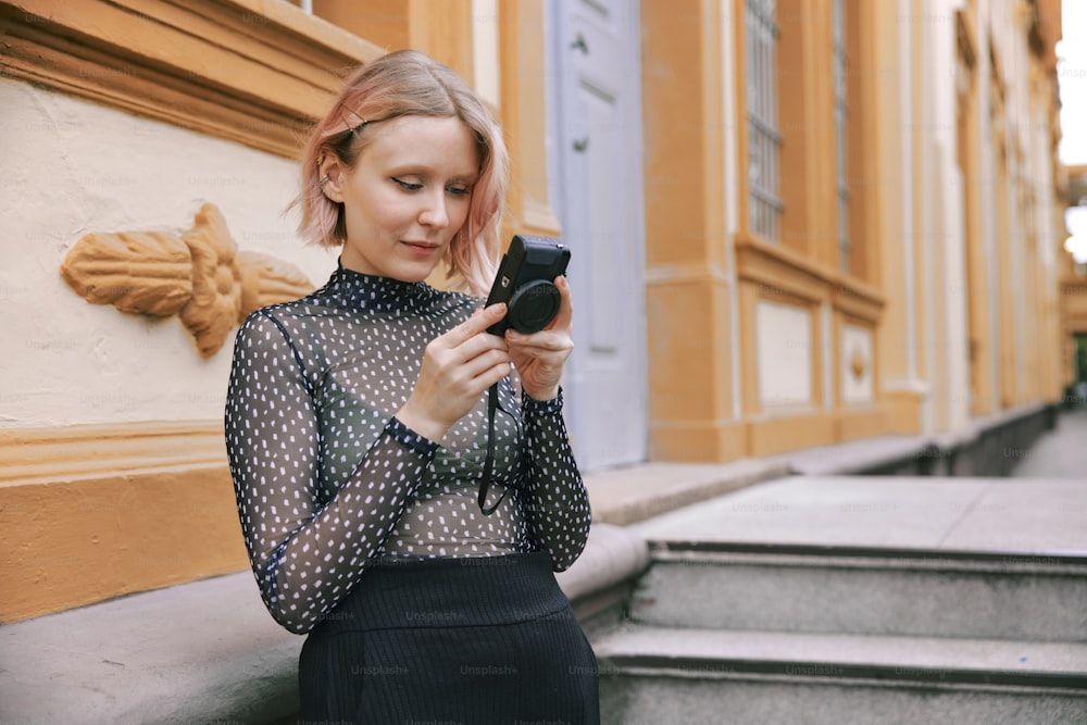 a woman in a polka dot shirt looking at her cell phone