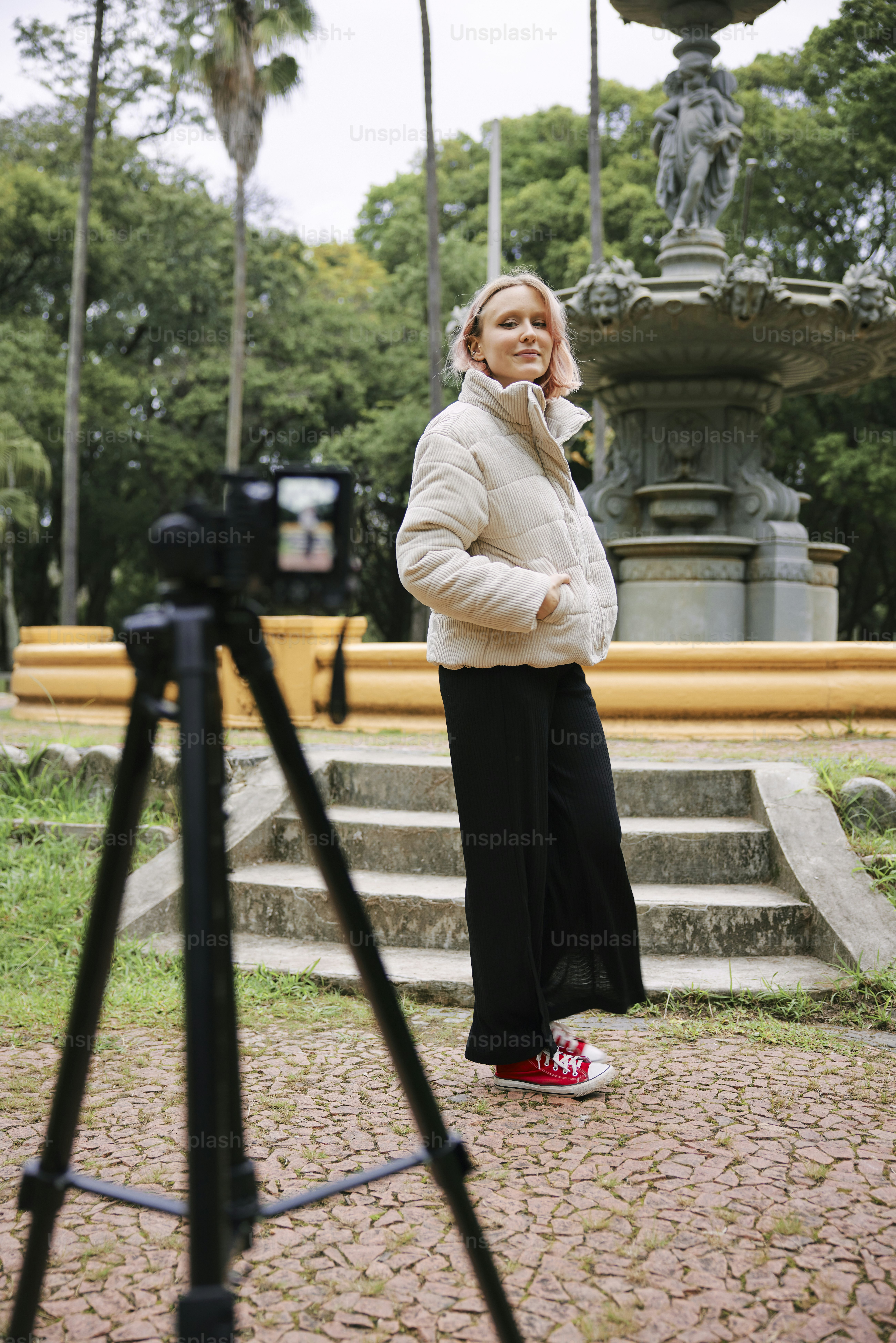 Una donna in piedi davanti a una fontana che parla al cellulare