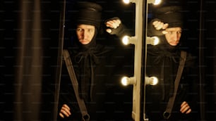 a man in a black outfit is looking at himself in a mirror