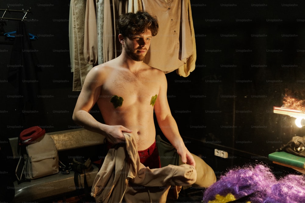 Un uomo a torso nudo in piedi accanto a una pila di vestiti