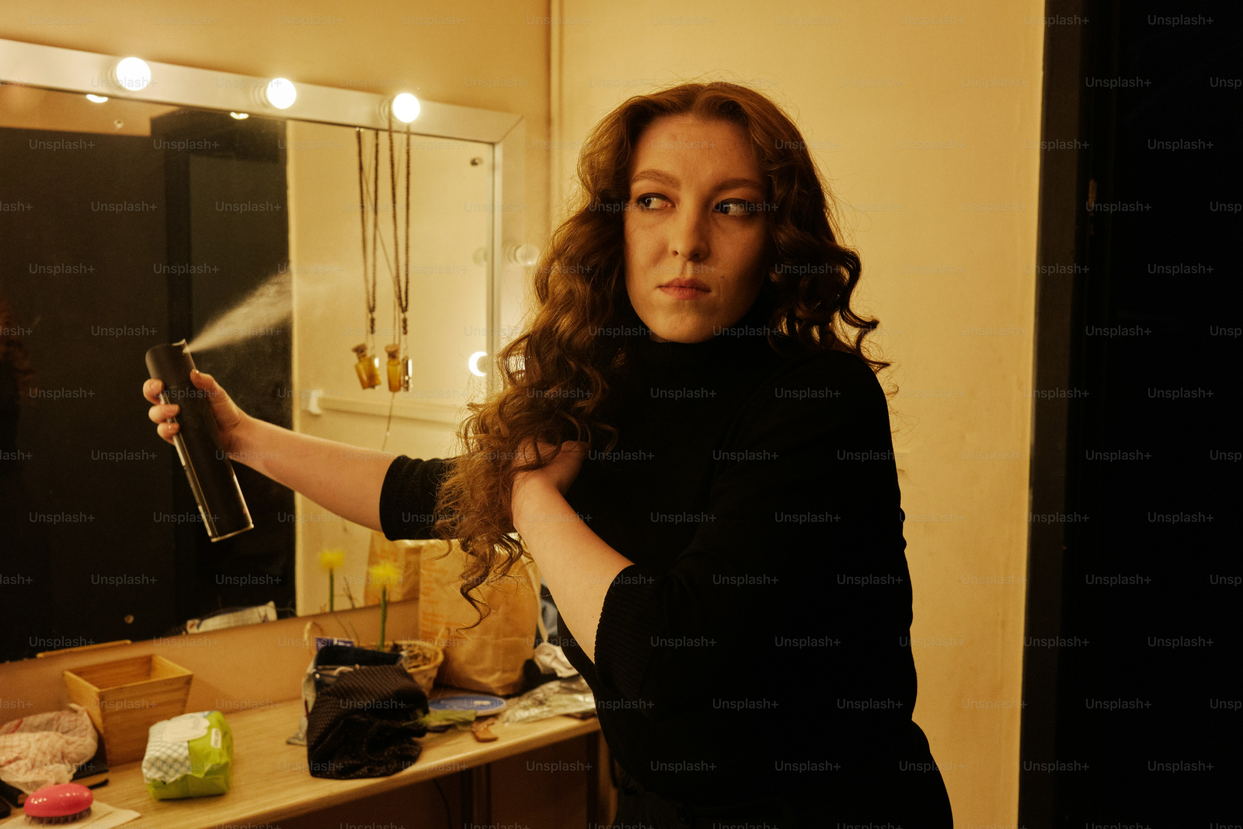Una mujer secándose el cabello frente a un espejo