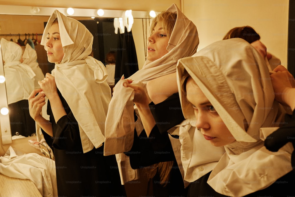 um grupo de mulheres em pé um ao lado do outro em frente a um espelho
