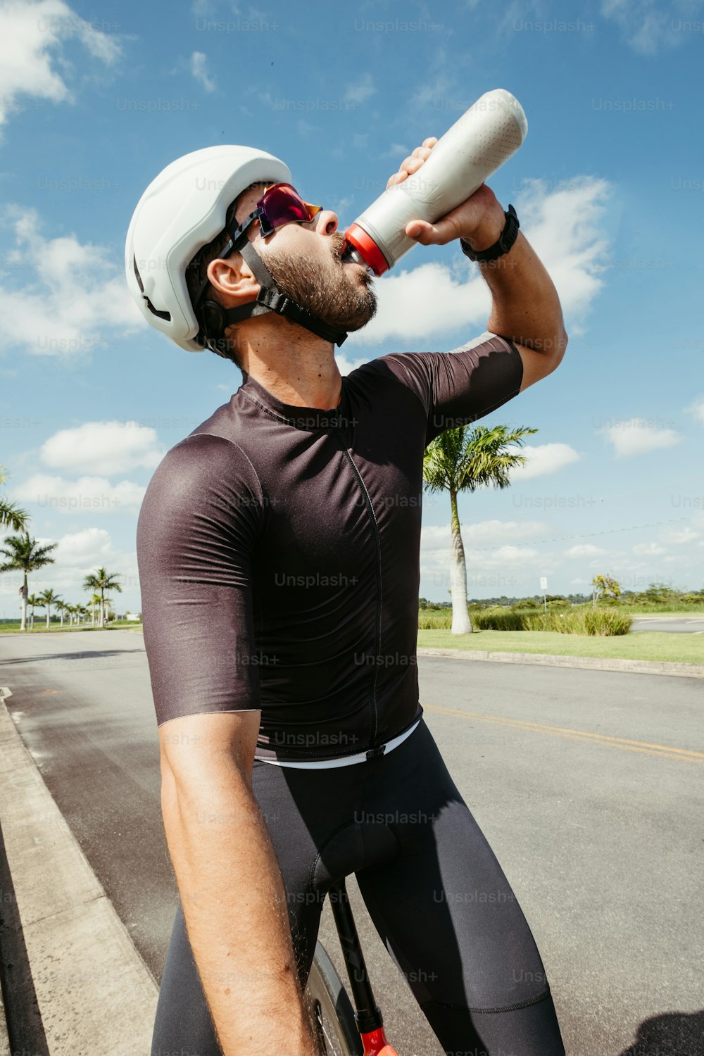 a man drinking water from a bottle while riding a bike