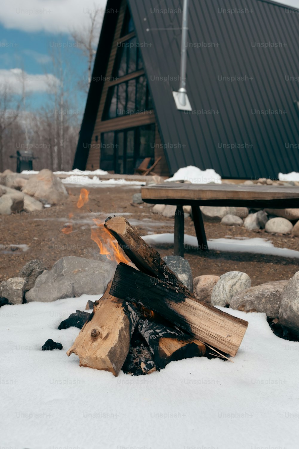 uma pilha de troncos sentada na neve ao lado de um prédio