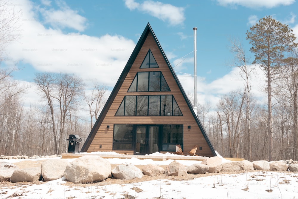 Una casa di legno con un tetto triangolare nella neve