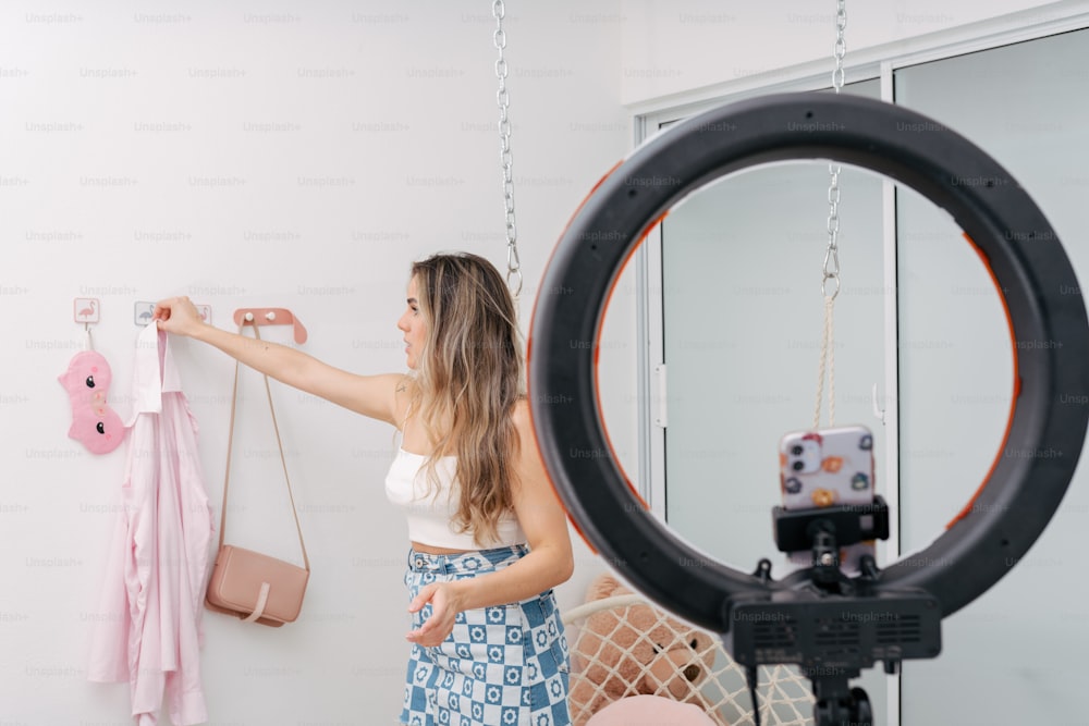 a woman in a white tank top is holding a pink purse