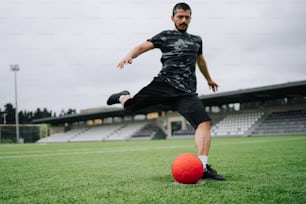 um homem chutando uma bola de futebol em um campo