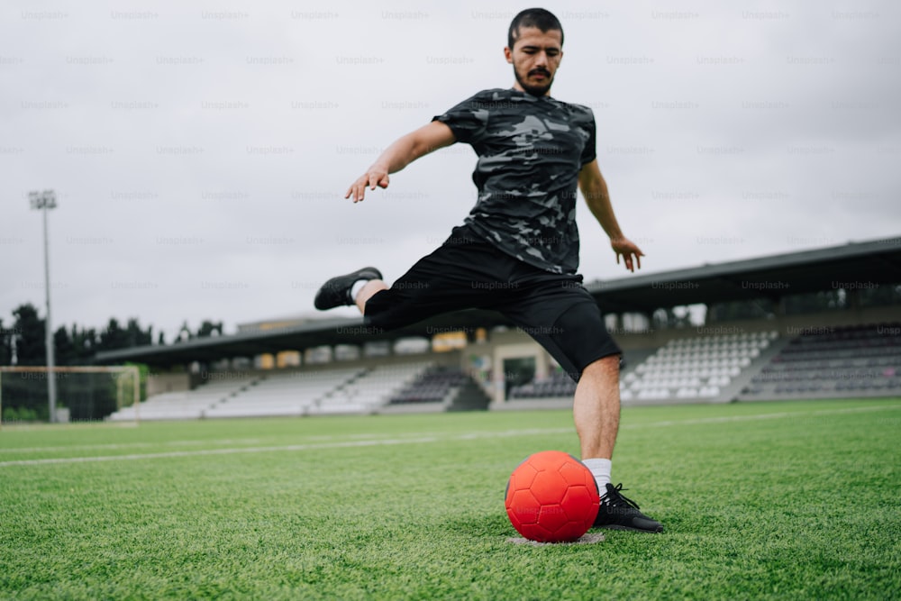 Un hombre pateando una pelota de fútbol en un campo