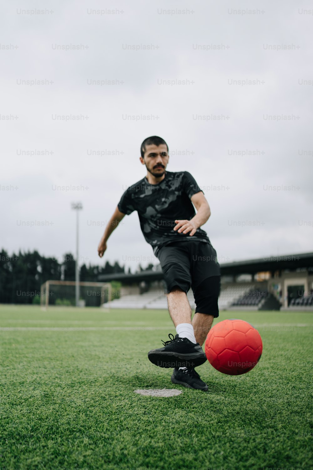 Un hombre pateando una pelota de fútbol en un campo