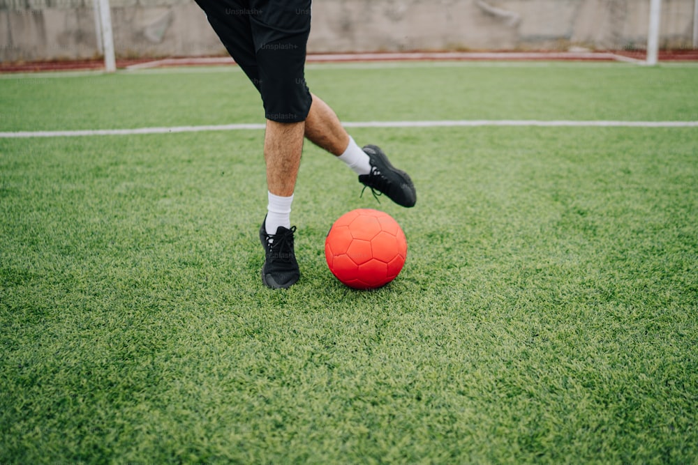 um homem chutando uma bola de futebol em um campo de futebol