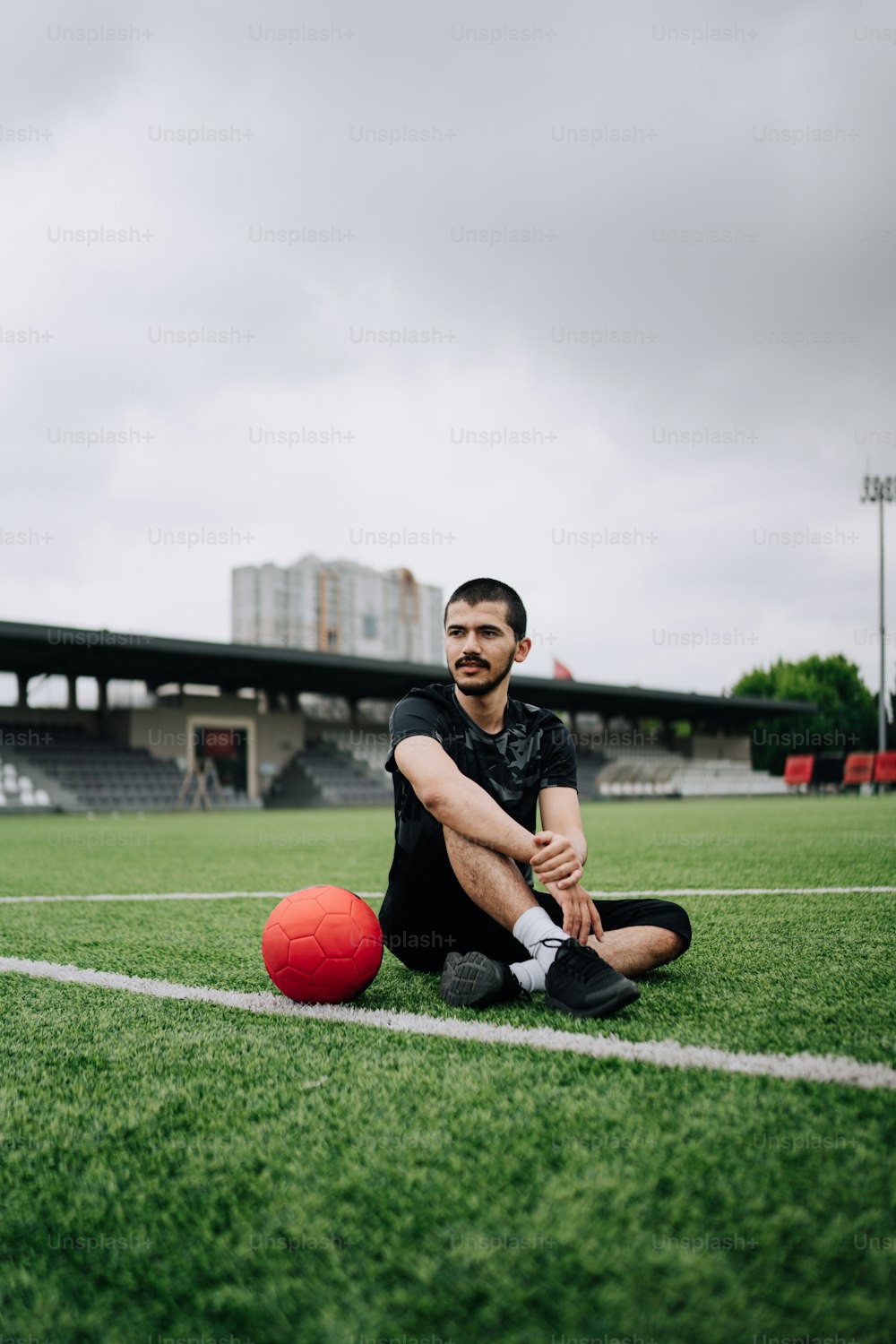Un hombre sentado en el suelo con una pelota de fútbol