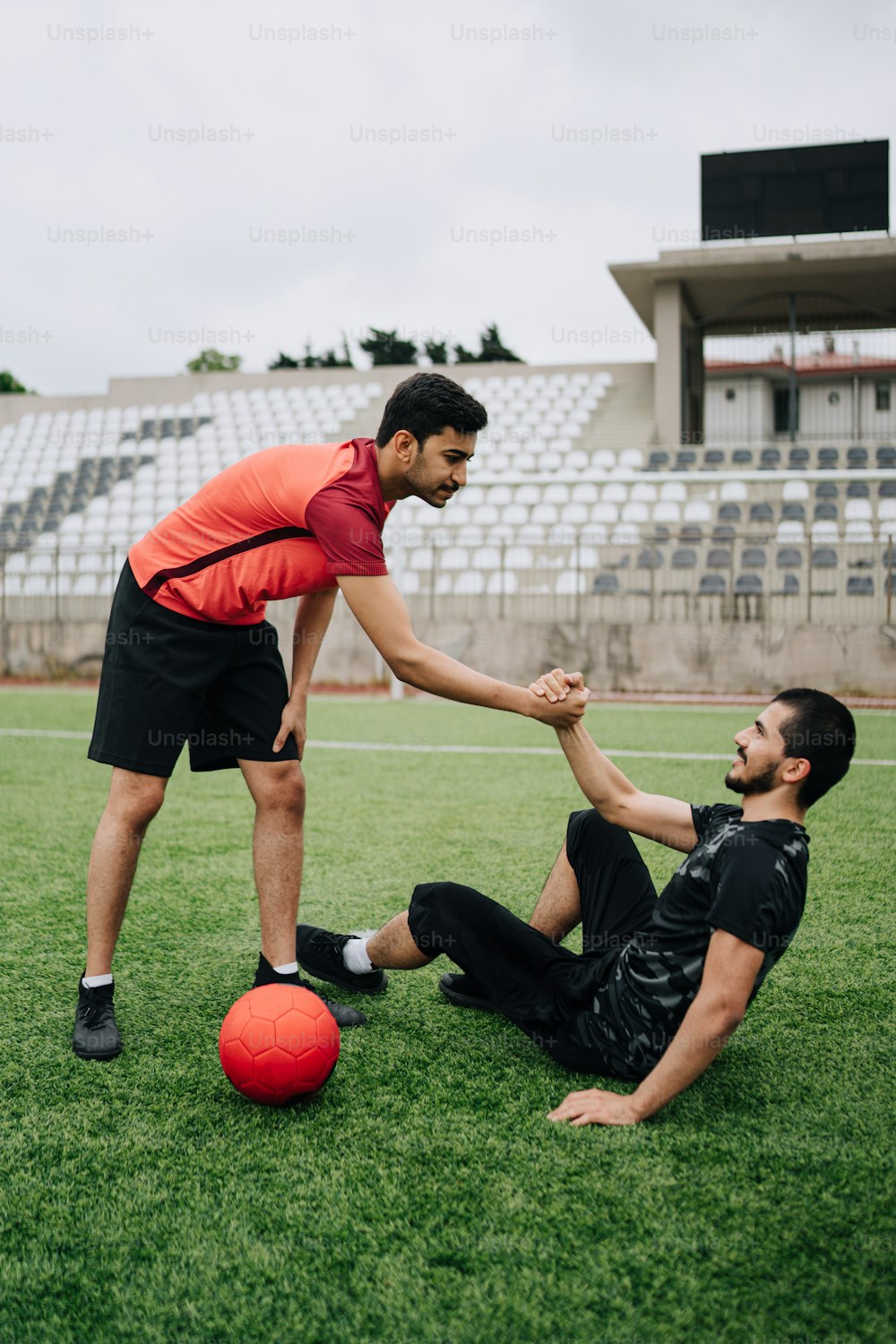 Un hombre está ayudando a otro hombre con un balón de fútbol