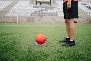 um homem ao lado de uma bola de futebol em um campo