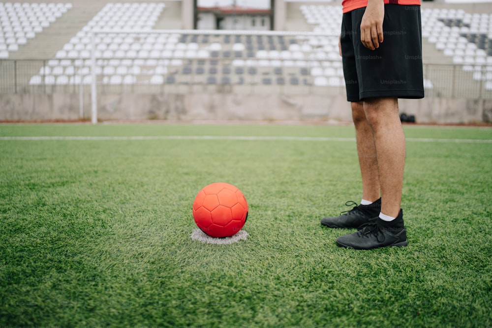 Un hombre parado junto a un balón de fútbol en un campo
