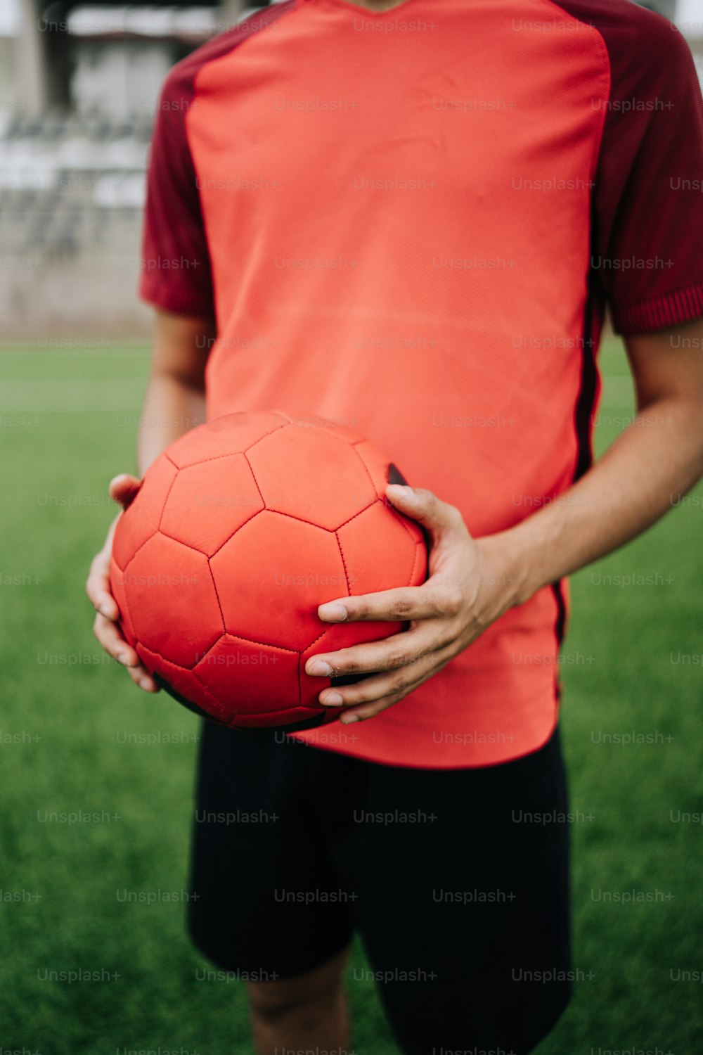 Un hombre sosteniendo un balón de fútbol rojo en sus manos