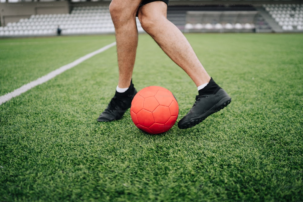 Un uomo in piedi sopra un pallone da calcio su un campo