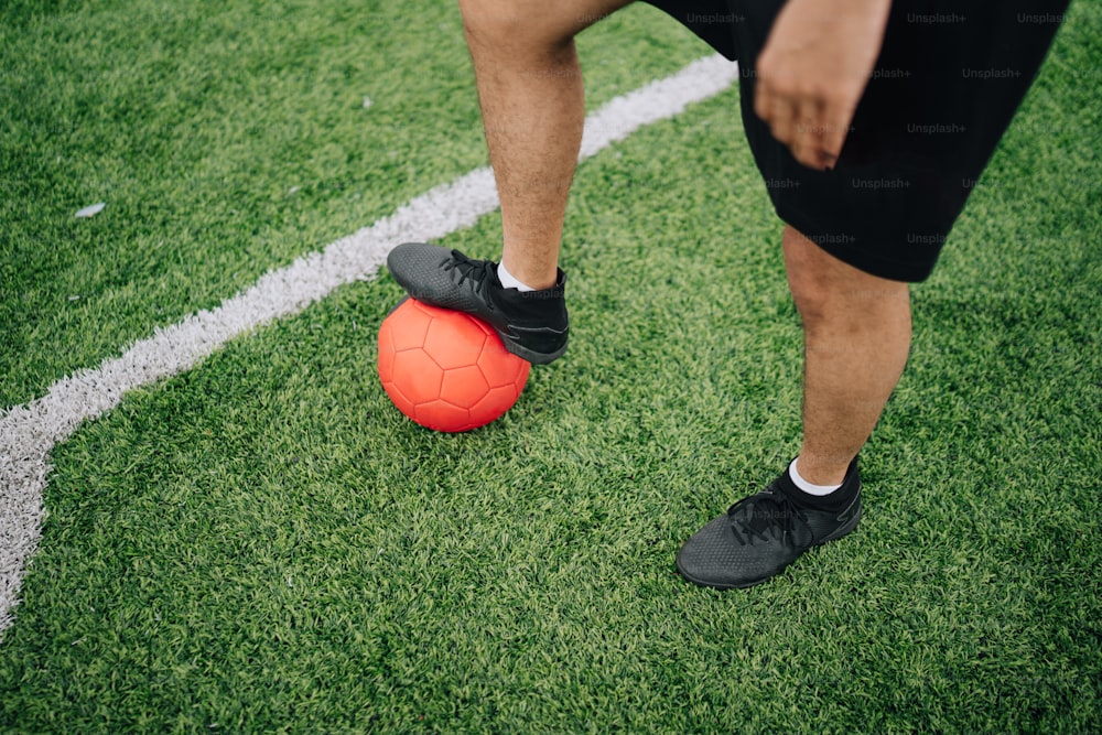 Un hombre parado encima de una pelota de fútbol en un campo