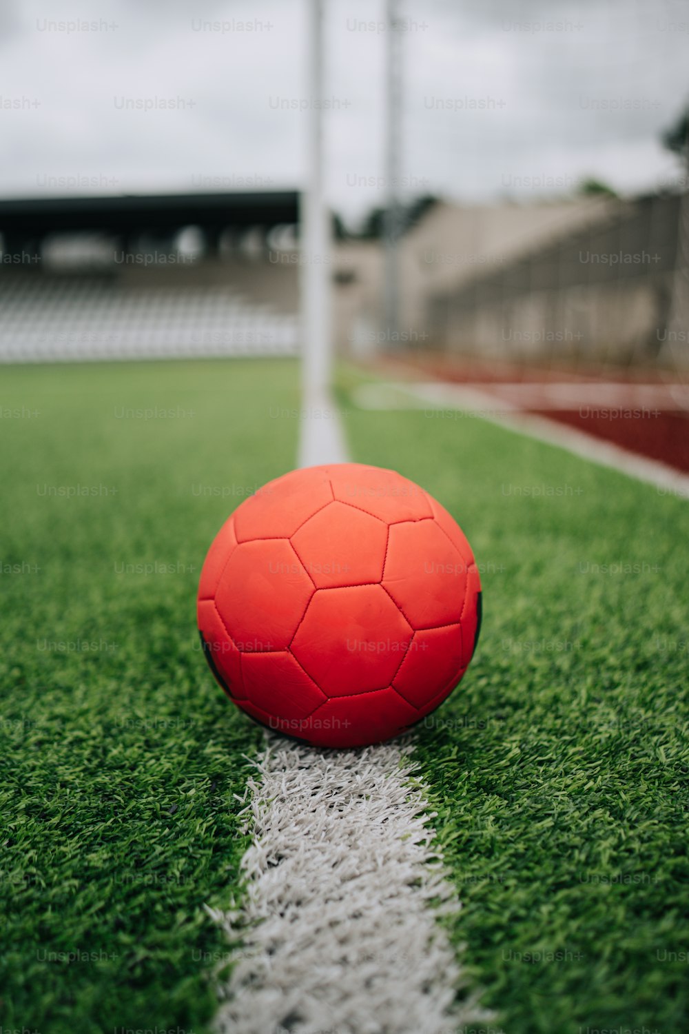 Una pelota de fútbol roja sentada encima de un campo de fútbol