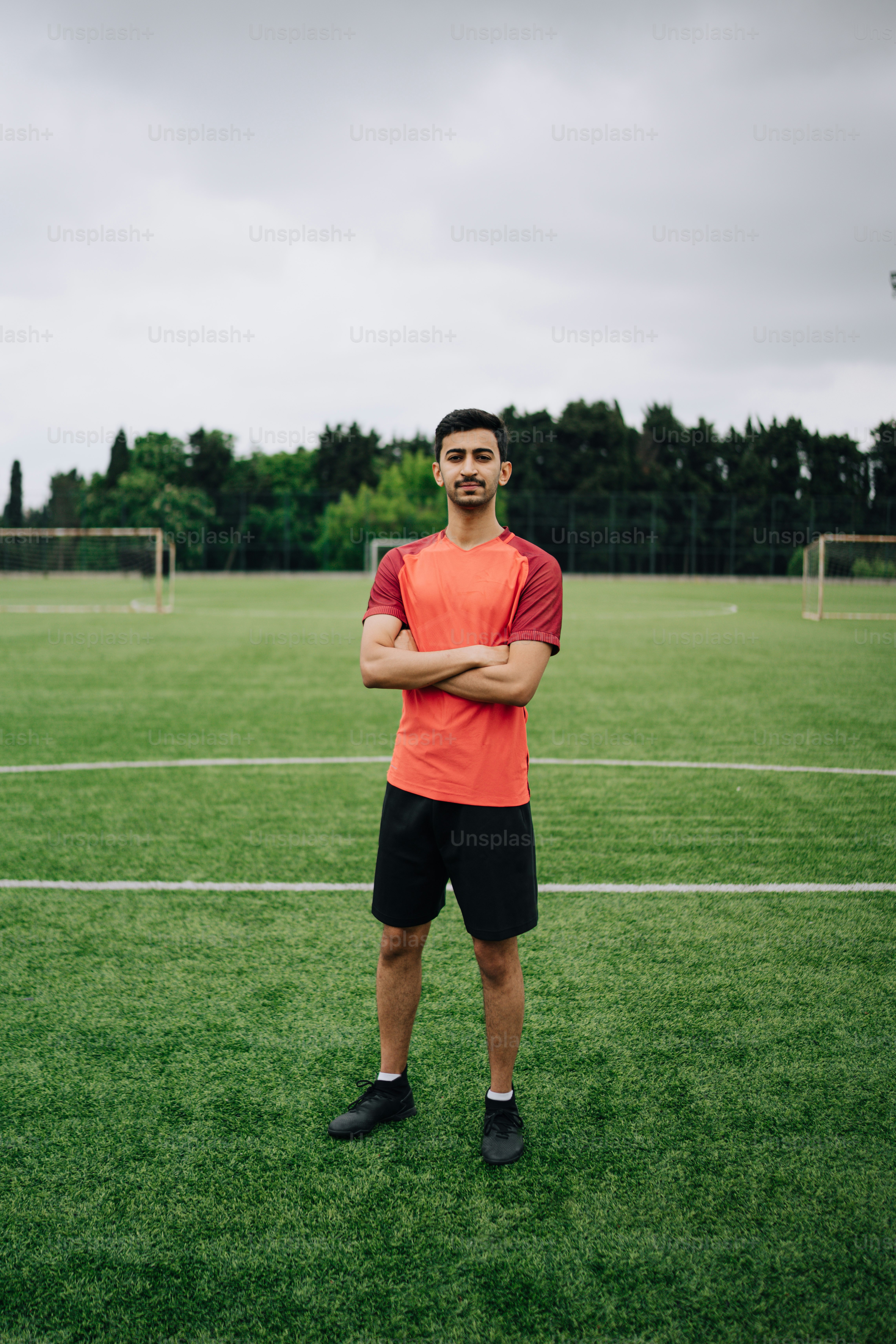 a man standing on a soccer field with his arms crossed