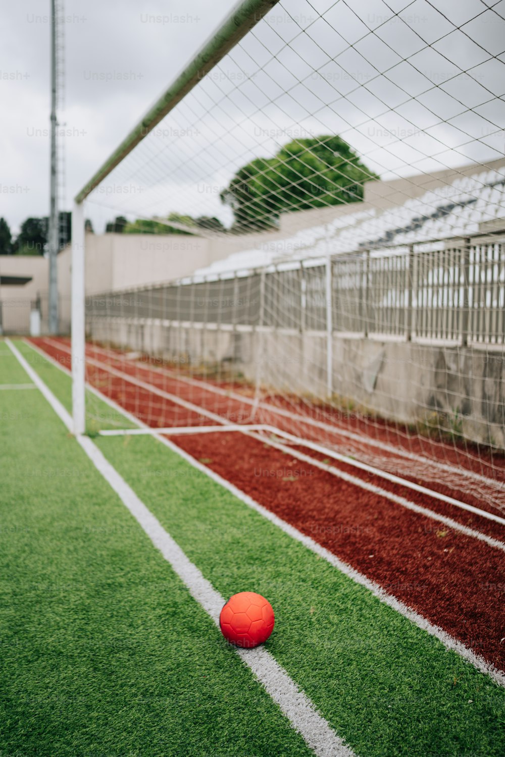 Un balón de fútbol rojo sentado encima de un campo verde