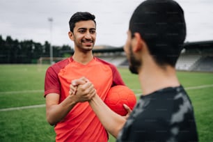 un hombre sosteniendo una pelota de fútbol frente a otro hombre
