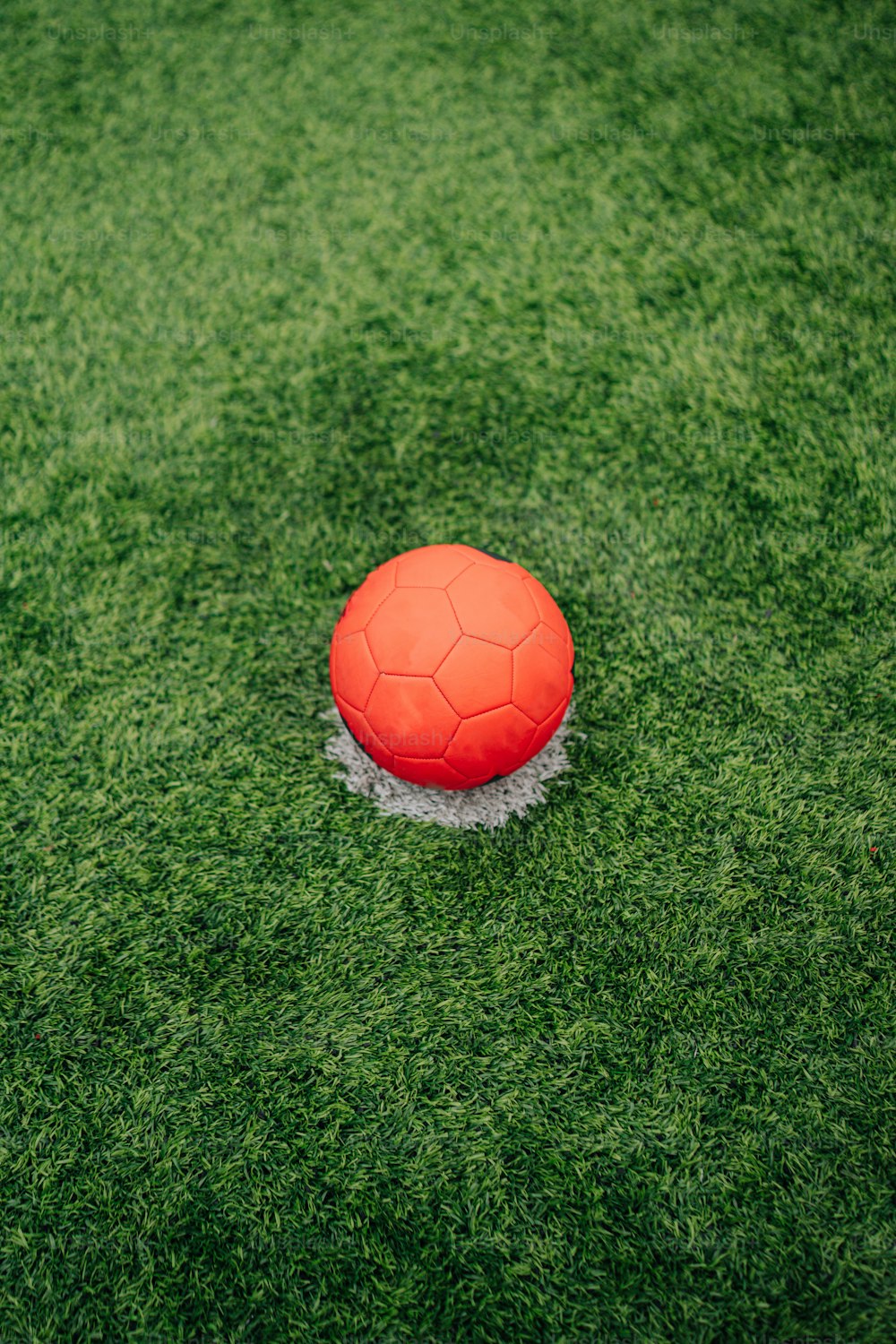 Un balón de fútbol rojo sentado encima de un exuberante campo verde