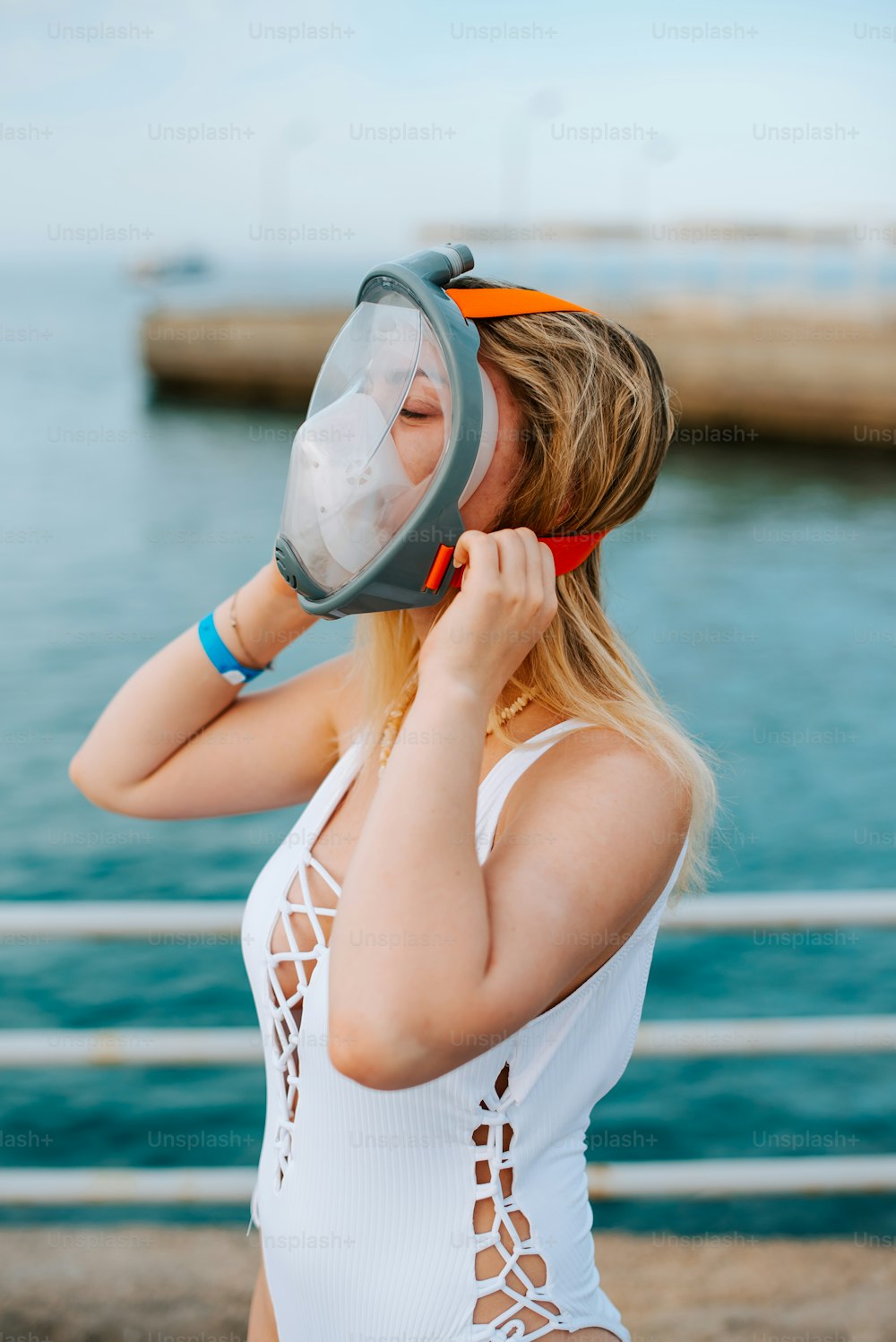 a woman in a white swimsuit holding a mask to her face