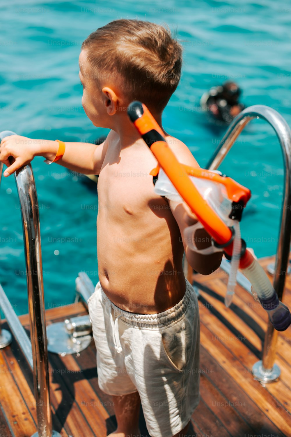 um garotinho em pé em uma doca com um colete salva-vidas ligado