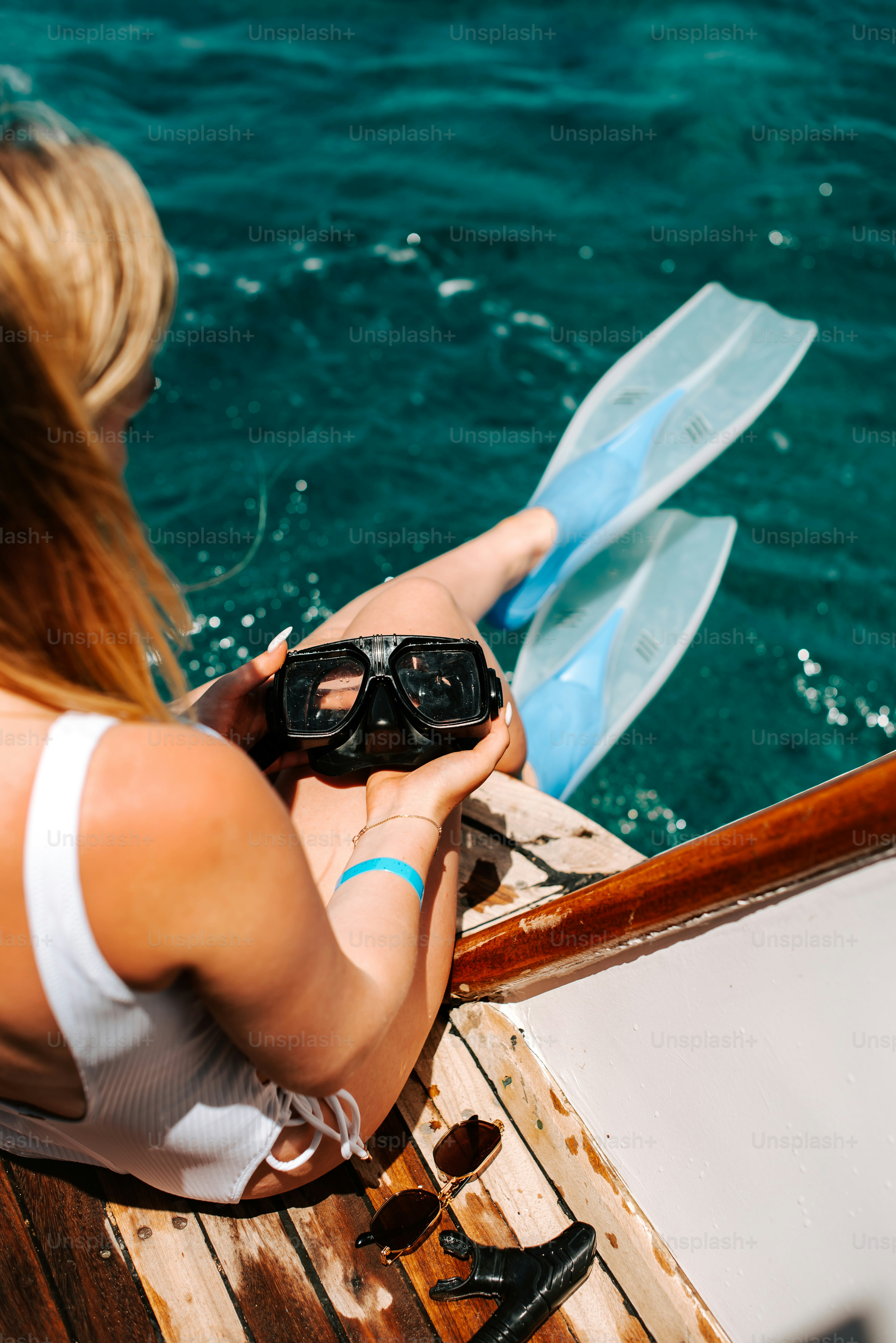 a woman sitting on a boat holding a pair of goggles