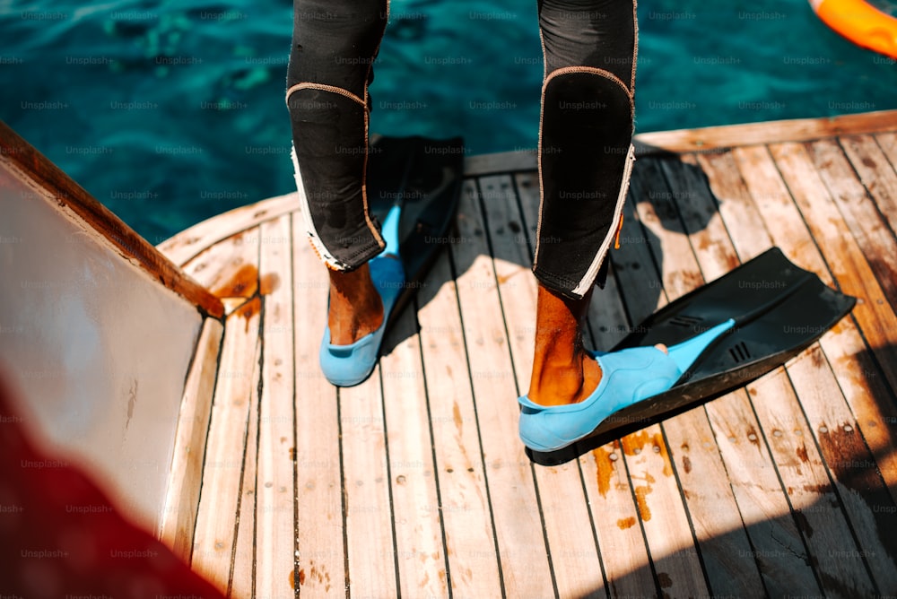 a person wearing blue shoes standing on a boat