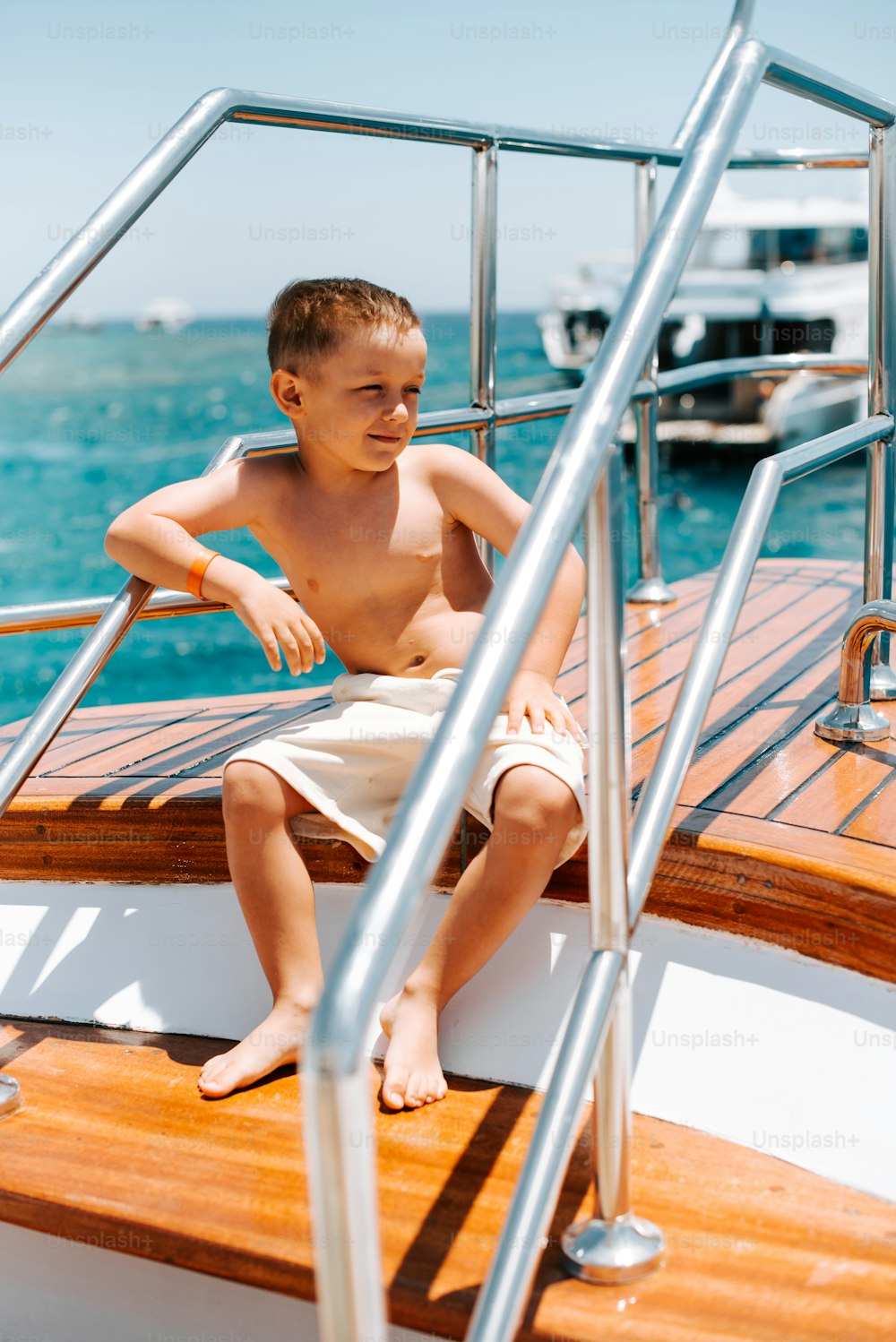 a young boy sitting on the deck of a boat