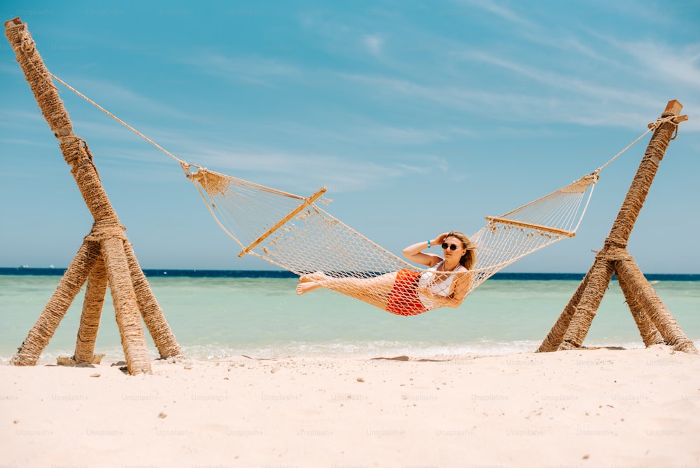 a woman laying in a hammock on the beach
