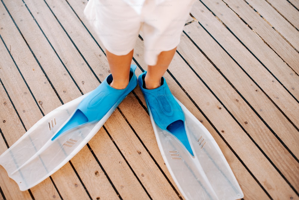 a person standing on a wooden deck wearing blue and white shoes