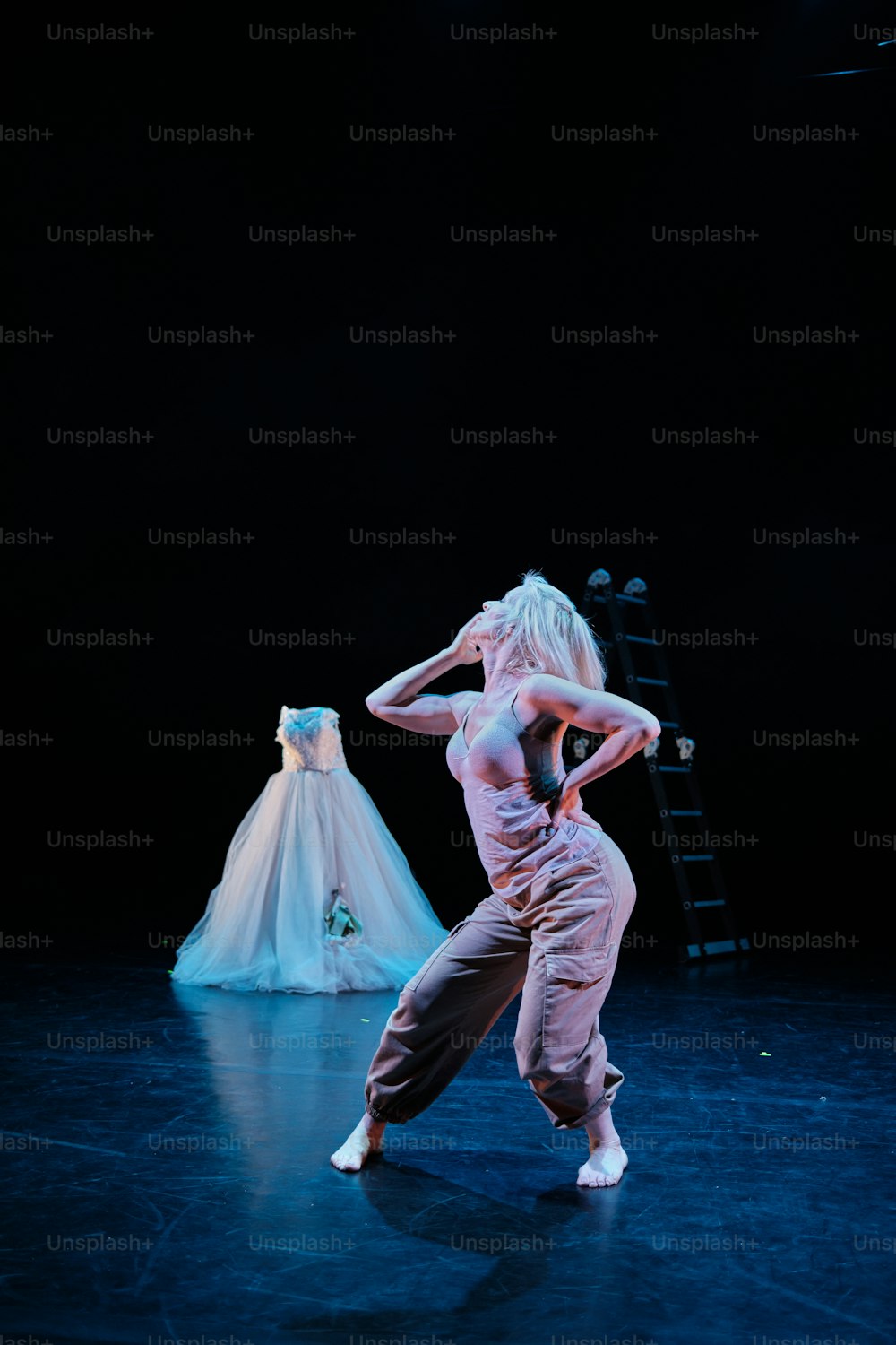 a woman is dancing on a stage with a dress behind her
