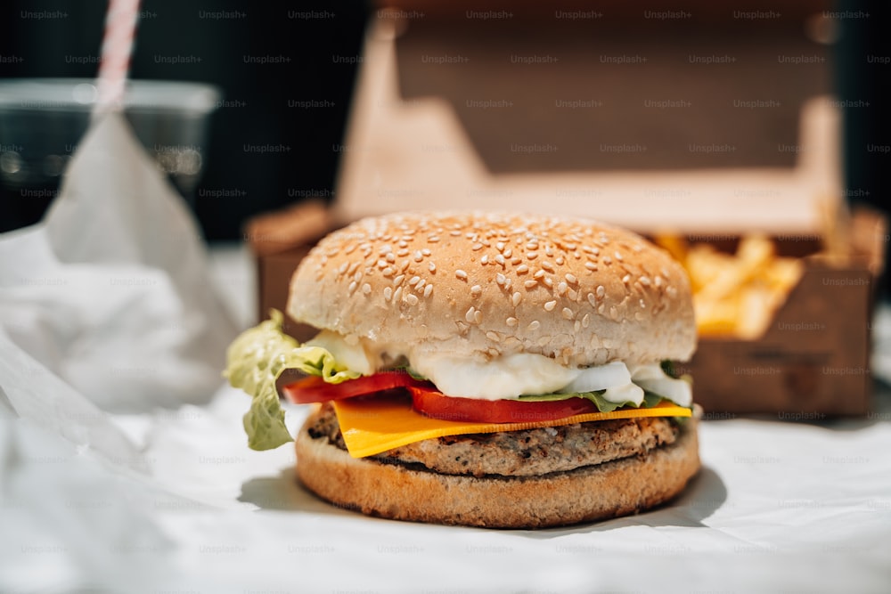 a hamburger sitting on top of a table next to a box of fries