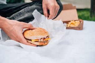 une personne tenant un hamburger à la main