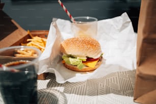a hamburger and fries on a table with a drink