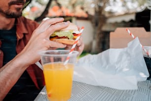 a man sitting at a table with a sandwich and orange juice