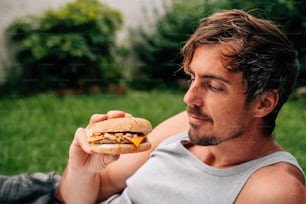 a man sitting in the grass eating a sandwich