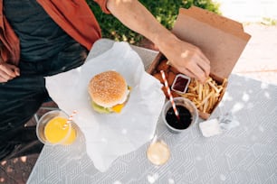 une personne assise à une table avec un hamburger et des frites