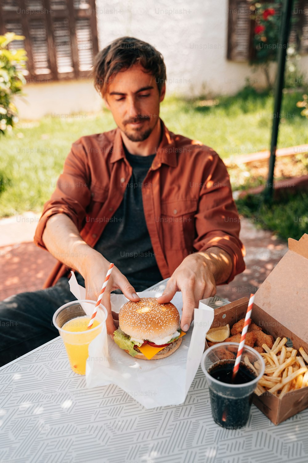 a man sitting at a table with a hamburger and fries