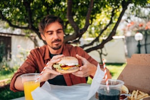 a man sitting at a table with a sandwich and drinks