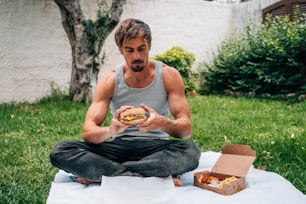 Ein Mann, der auf einer Decke sitzt und ein Sandwich isst