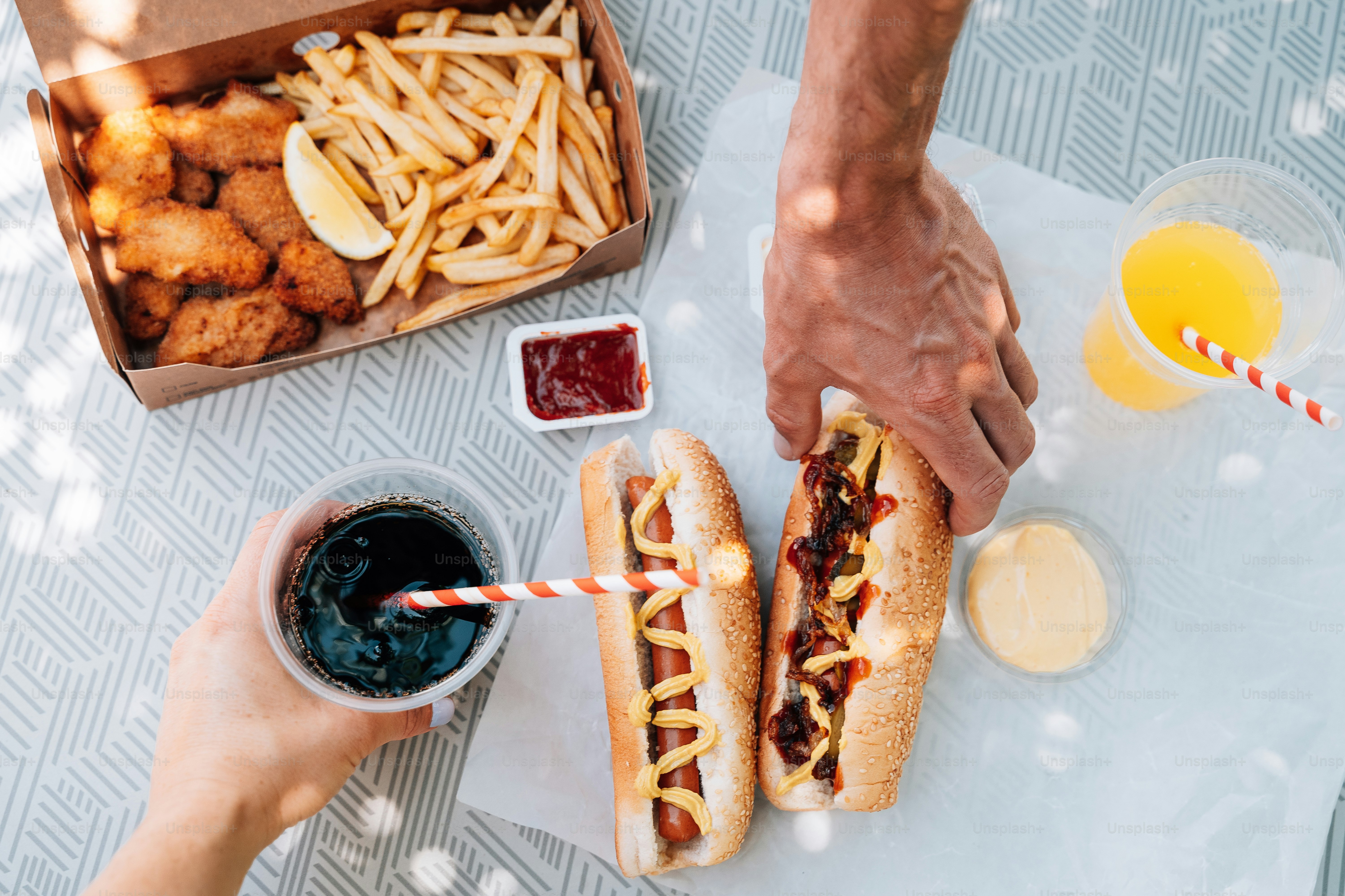 a person holding a hot dog next to a box of fries and ketchup