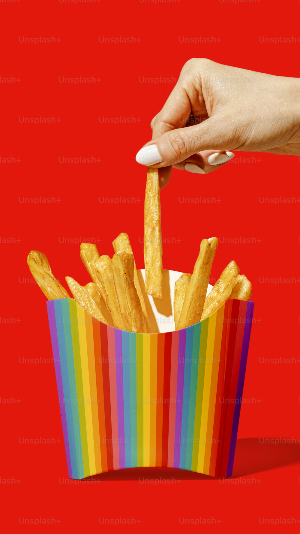 a hand reaching for french fries in a colorful box