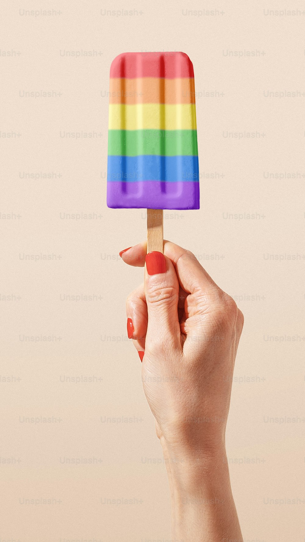 uma mão segurando um picolé com um arco-íris