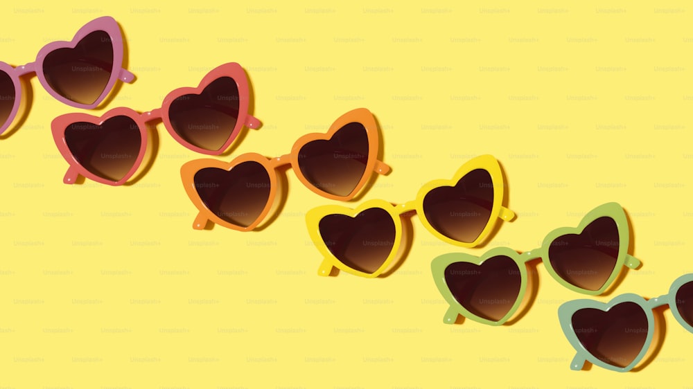 una fila di occhiali da sole a forma di cuore su sfondo giallo