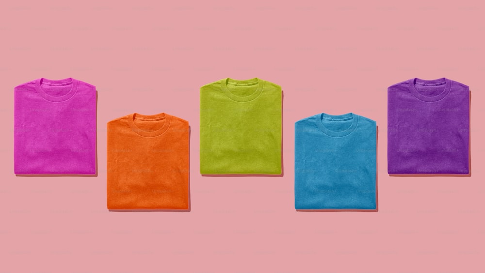 um grupo de cinco t-shirts em um fundo rosa