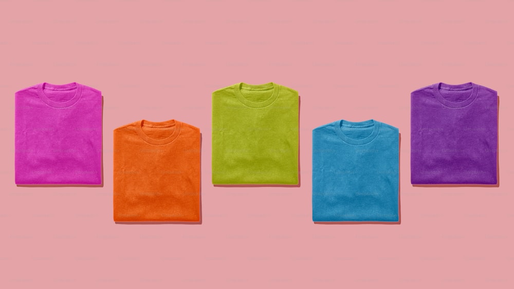a group of five t - shirts on a pink background