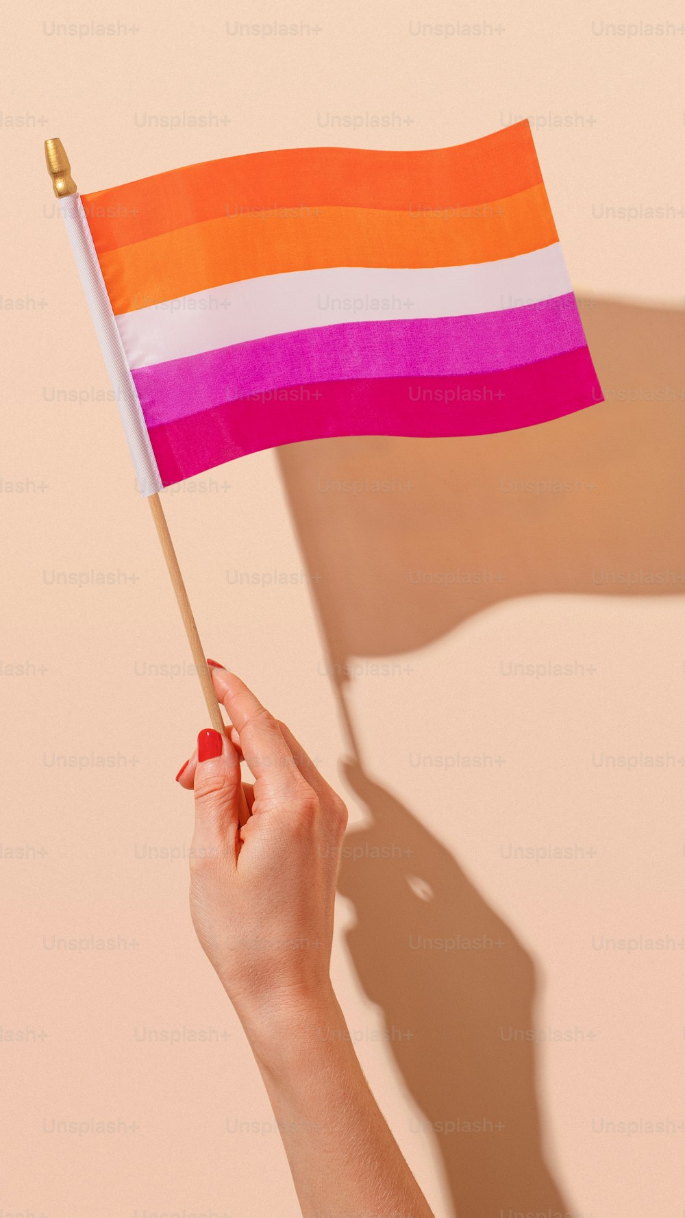 Una mujer sosteniendo una bandera del arco iris en la mano